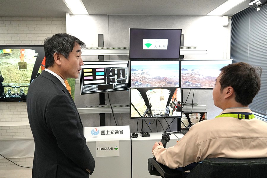 建機遠隔操作システムの操作について話を聞く佐々木国交副大臣（左）（日本工業経済新聞社【建設メール】より）